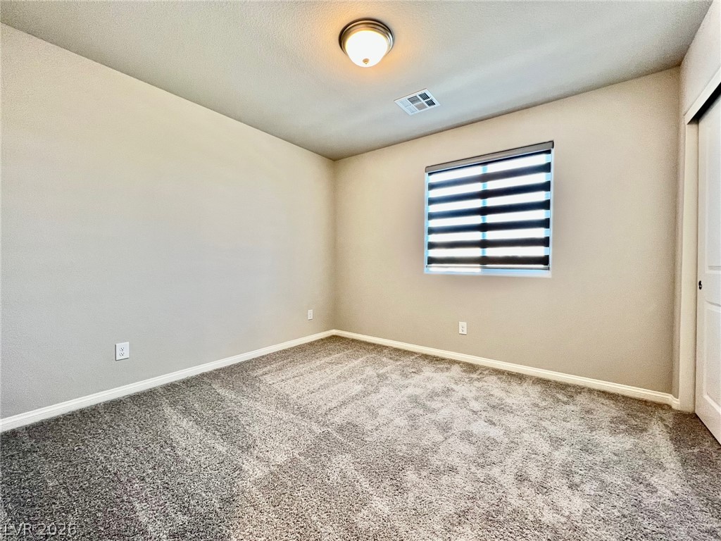 7845 Morganite Avenue Las Vegas, NV 89113 - Photo 17 of 21 A well-lit bedroom offering plush carpeting and a window with modern blinds for light control.