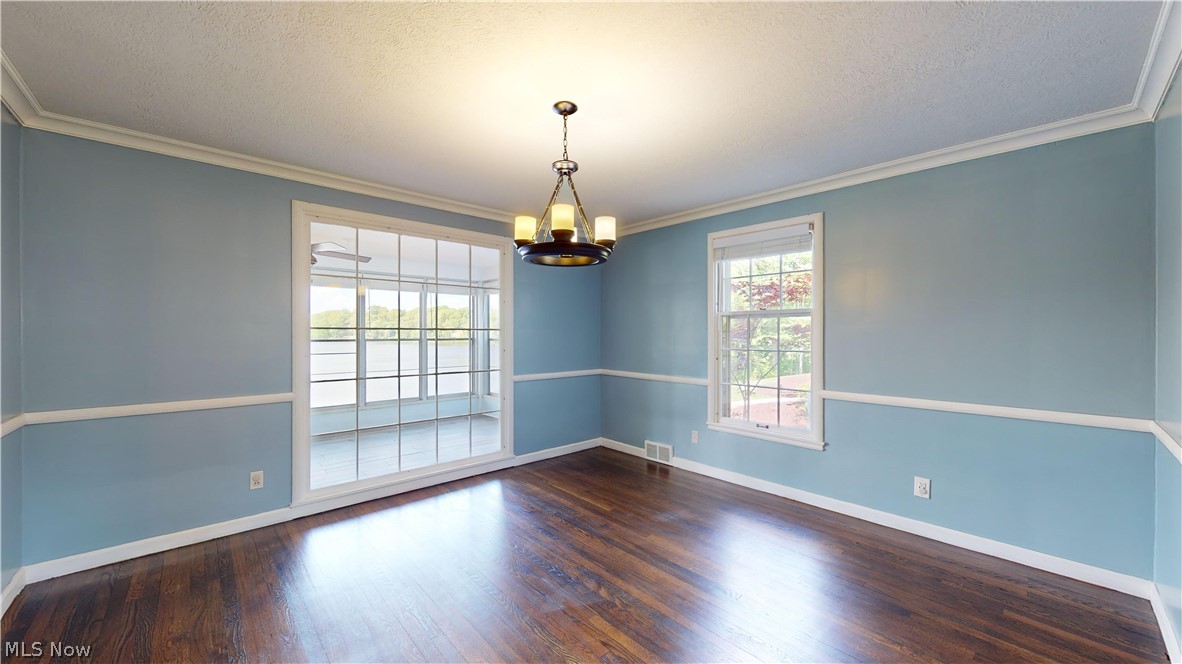 7421 Diagonal Road Kent, OH 44240 - Photo 19 of 48 Empty room featuring an inviting chandelier, a textured ceiling, dark hardwood / wood-style floors, and crown molding