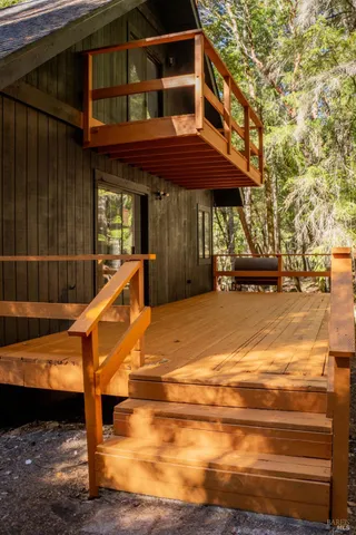 a view of a patio with table and chairs under an umbrella with large trees