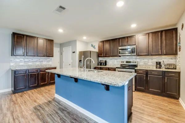 a kitchen with stainless steel appliances granite countertop wooden cabinets a stove top oven a sink and dishwasher