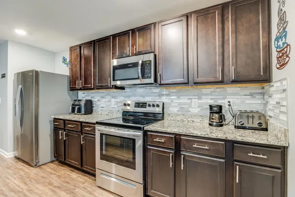 a kitchen with granite countertop wooden cabinets stainless steel appliances and a sink