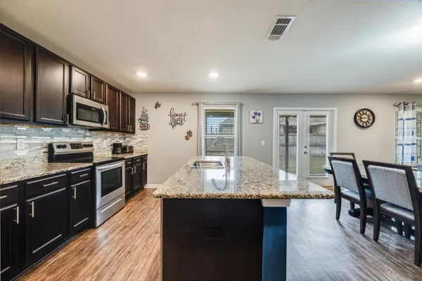 a large kitchen with granite countertop lots of counter space and stainless steel appliances