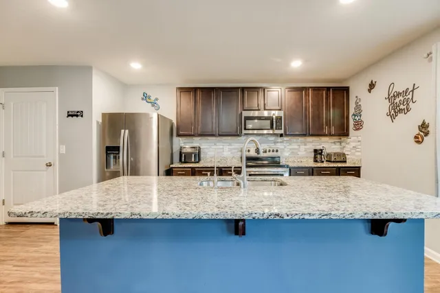 a kitchen with stainless steel appliances granite countertop a sink refrigerator and cabinets