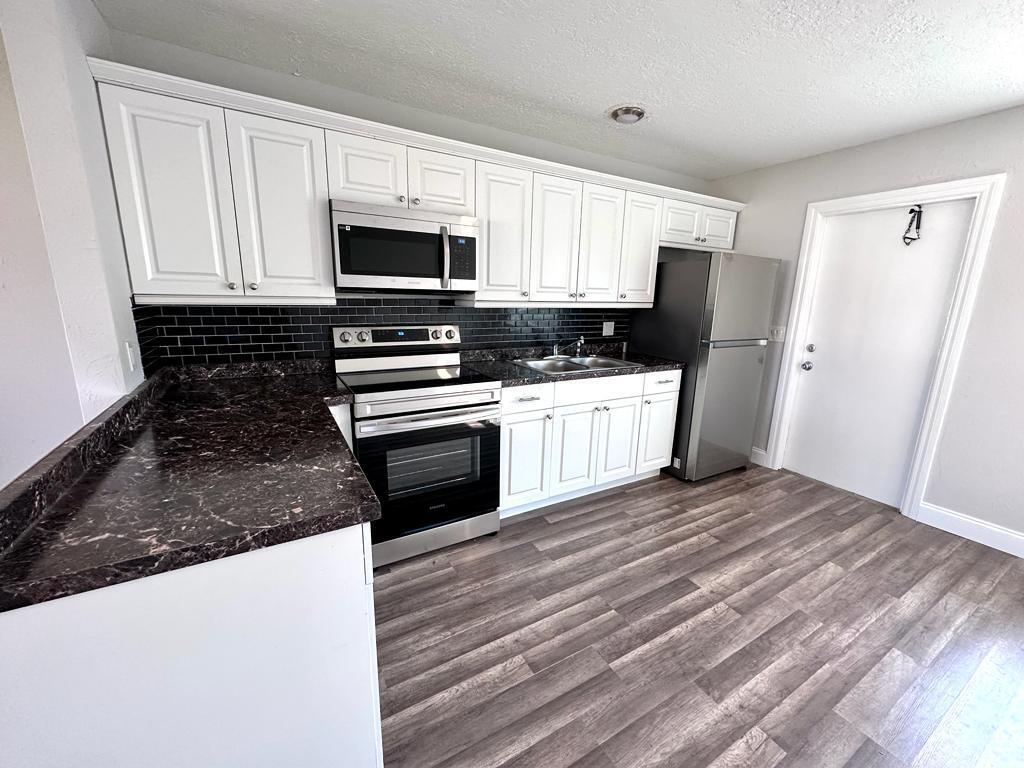 a kitchen with stainless steel appliances granite countertop a stove a sink and a refrigerator