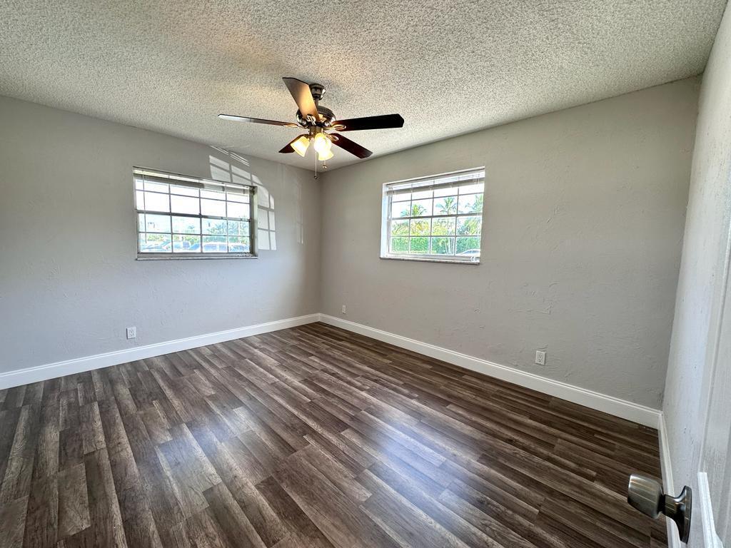 848 Center Street, Unit 3 Jupiter, FL 33458 - Photo 3 of 9 an empty room with wooden floor fan and windows