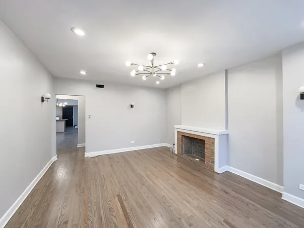 a view of an empty room with wooden floor and a fireplace