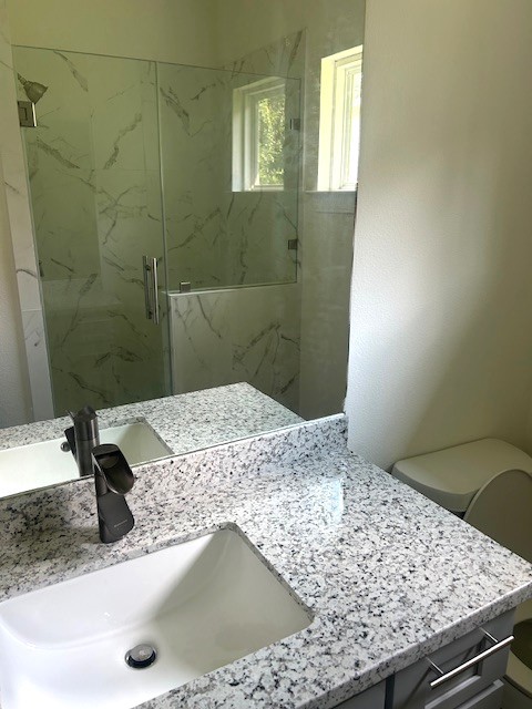 15010 Austin Road Willis, TX 77378 - Photo 17 of 22 a bathroom with a granite countertop sink a toilet and mirror