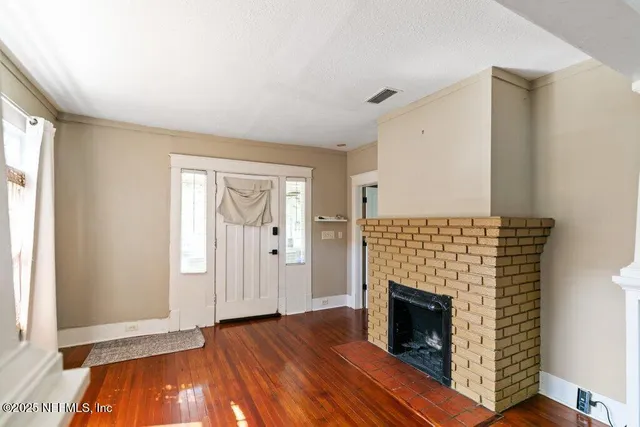 a view of a livingroom with wooden floor and a fireplace