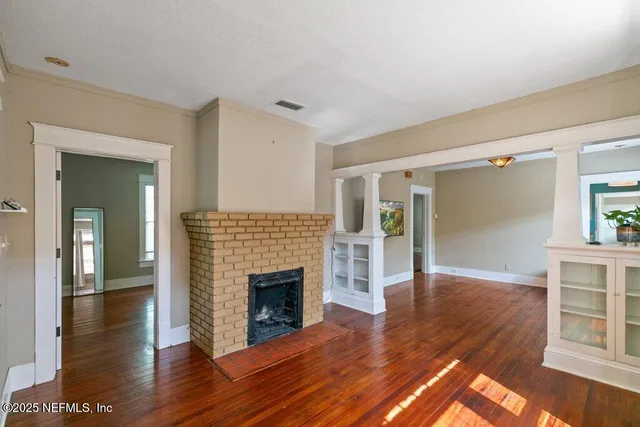a view of a livingroom with wooden floor and a fireplace
