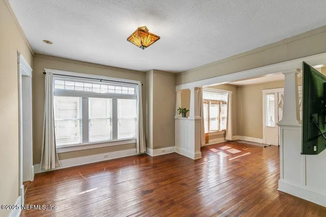 a view of an empty room with a window and wooden floor
