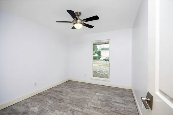 an empty room with a window and a ceiling fan