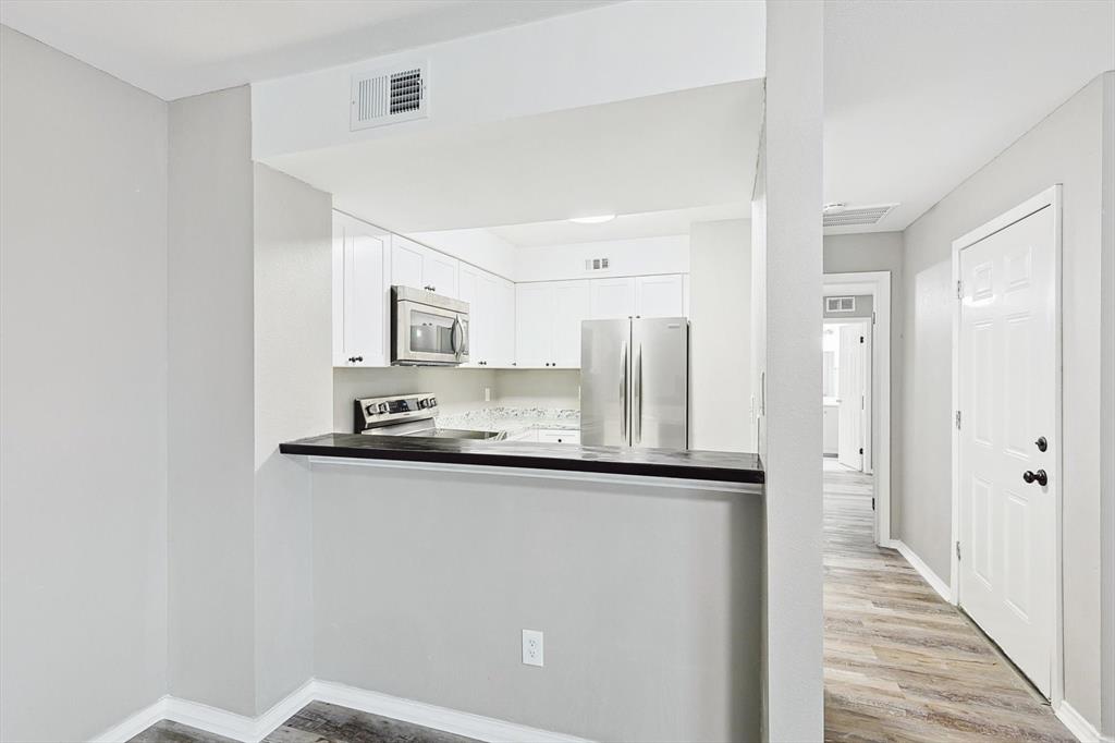 9805 Walnut Street, Unit 201 Dallas, TX 75243 - Photo 7 of 26 Kitchen with appliances with stainless steel finishes, white cabinetry, and light wood-type flooring