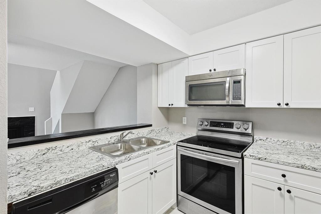9805 Walnut Street, Unit 201 Dallas, TX 75243 - Photo 9 of 26 Kitchen with sink, white cabinets, light stone countertops, and stainless steel appliances