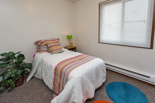 a bedroom with a bed lamp and a potted plant