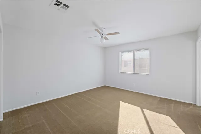 an empty room with a window and a fan
