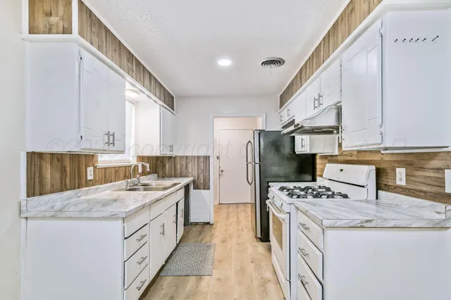 a kitchen with stainless steel appliances kitchen island granite countertop a sink stove and refrigerator