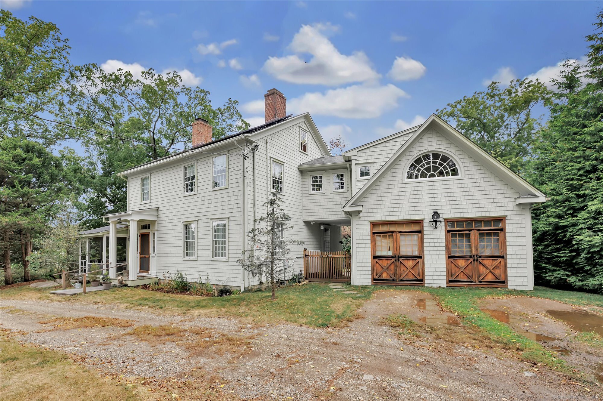 a view of a white house next to a yard and large trees