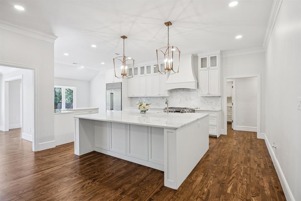 6848 Midcrest Drive Dallas, TX 75254 - Photo 7 of 38 a large kitchen with kitchen island white cabinets and wooden floor