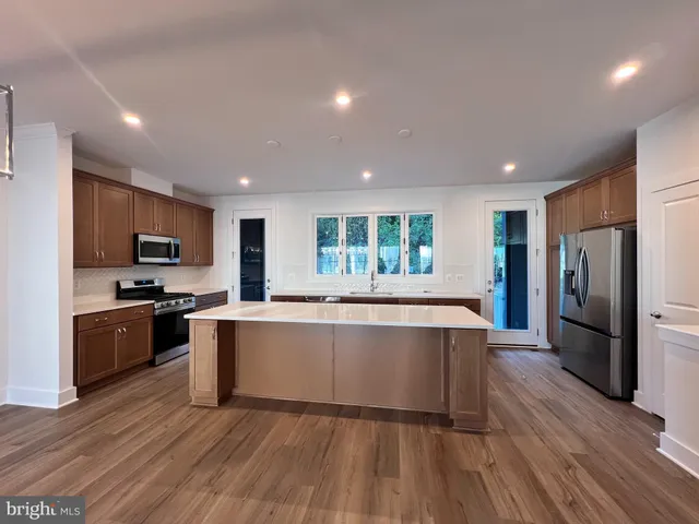 a large kitchen with stainless steel appliances lots of counter space and wooden floor