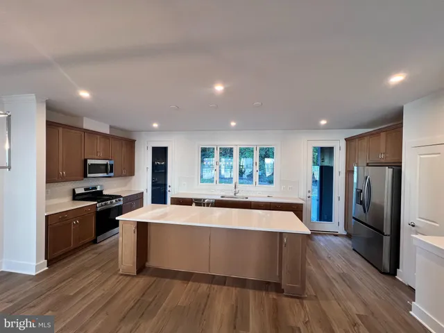 an empty room with wooden floor and kitchen view