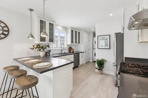 a kitchen with stainless steel appliances granite countertop a sink a stove and a wooden floor
