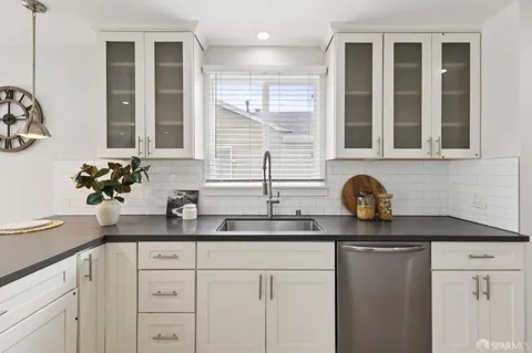 a kitchen with stainless steel appliances granite countertop white cabinets and a potted plant