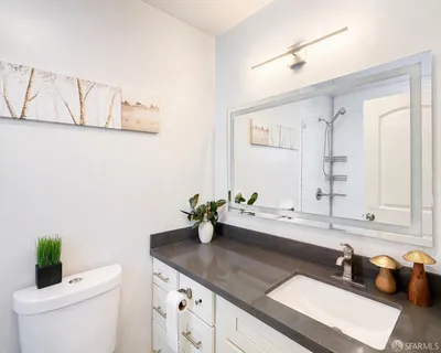 a bathroom with a granite countertop sink mirror and a toilet