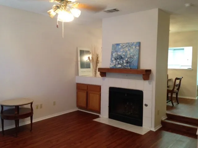 a view of an empty room with wooden floor and fireplace