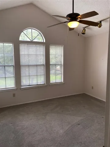 an empty room with windows and chandelier fan
