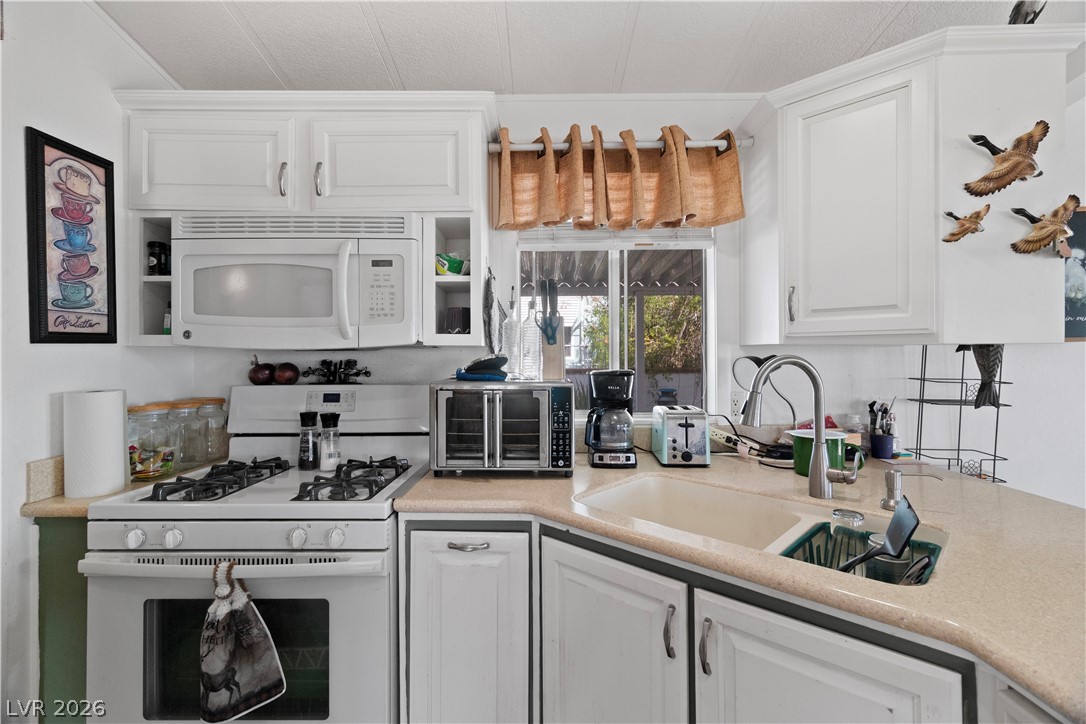 1655 Granada Street Laughlin, NV 89029 - Photo 16 of 76 Kitchen featuring white appliances, light countertops, white cabinetry, and open shelves