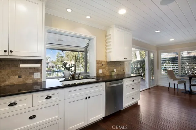 a kitchen with granite countertop white cabinets and white appliances with wooden floor