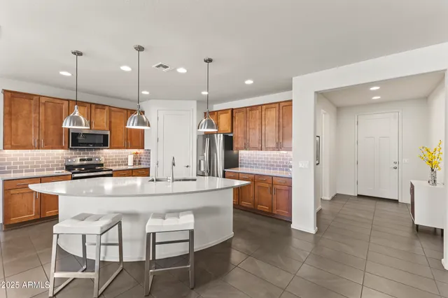 a kitchen with a refrigerator a stove top oven a sink a dining table and chairs