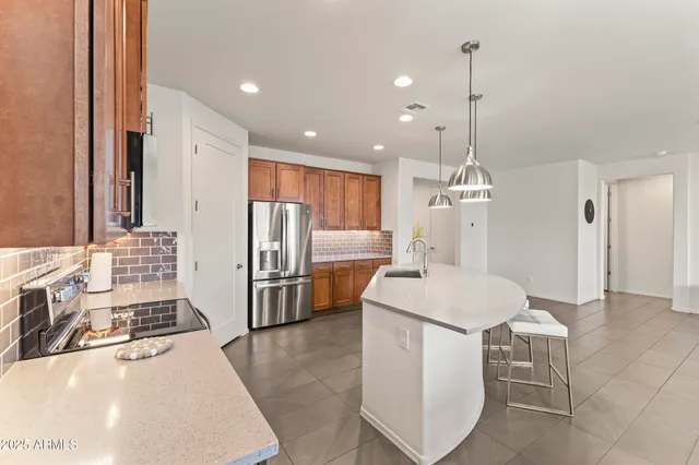 a large kitchen with kitchen island granite countertop a stove a sink a refrigerator and a cabinets