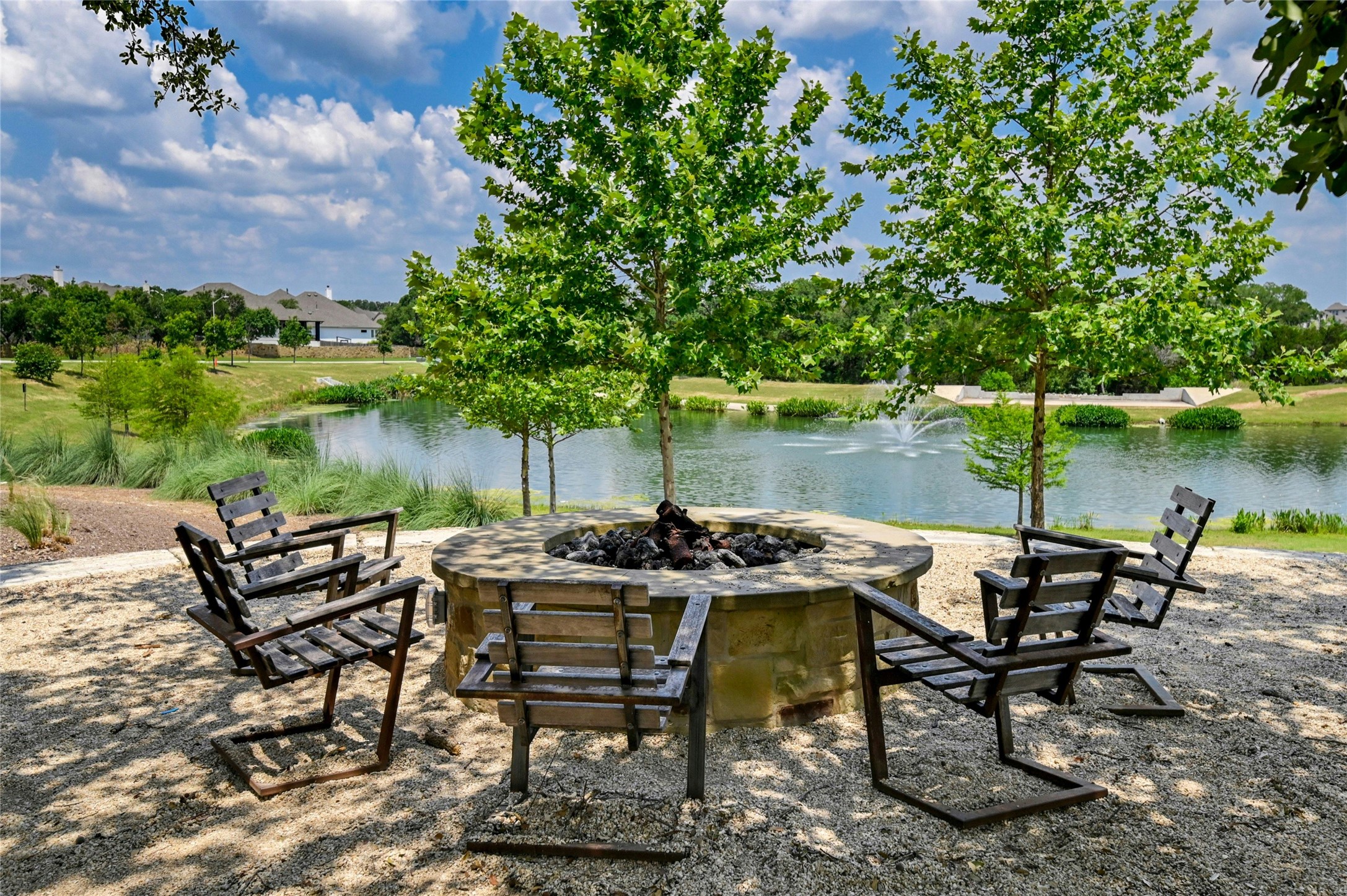 1140 Bryson Rdg Trail Leander, TX 78641 - Photo 38 of 39 Outdoor fire pit area with seating, overlooking a serene body of water with a fountain