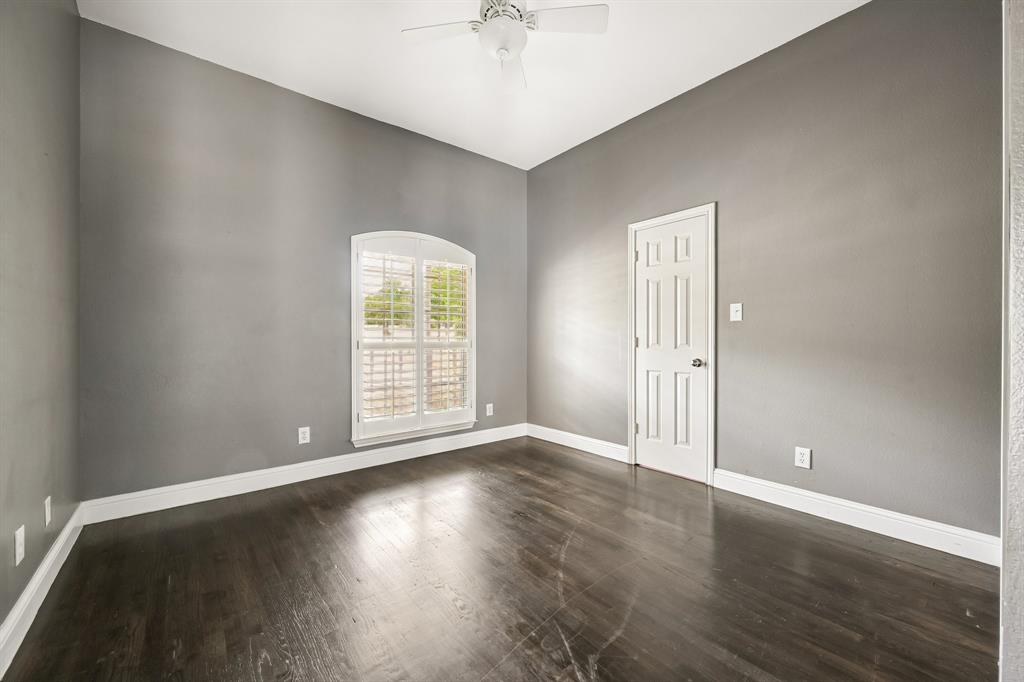 1380 Meandro Ria Lane Fairview, TX 75069 - Photo 19 of 39 Dark wood-finish flooring, arched window with plantation shutters, ceiling fan, and white trim accents