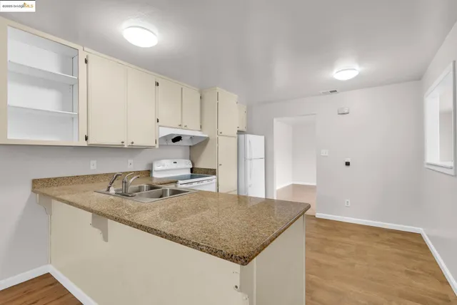 a kitchen with stainless steel appliances granite countertop a sink and white cabinets with wooden floor