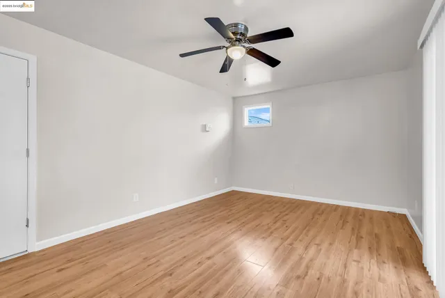 an empty room with wooden floor and ceiling fan
