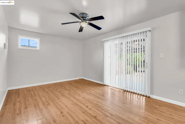 an empty room with wooden floor fan and windows