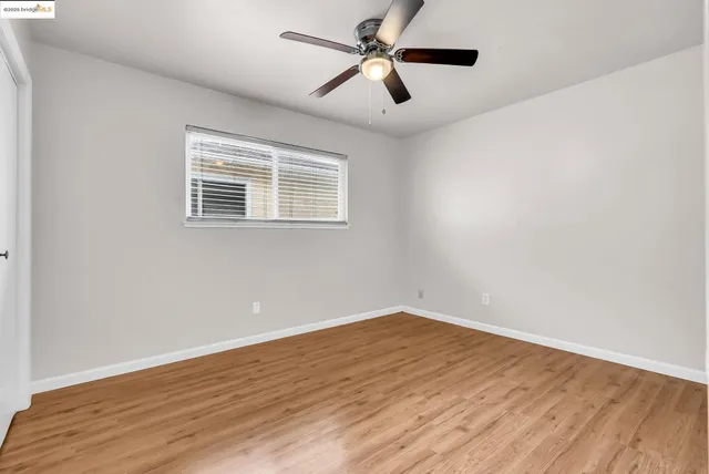 an empty room with wooden floor fan and windows