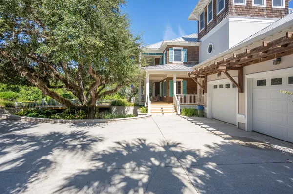 a front view of a building with garden and trees
