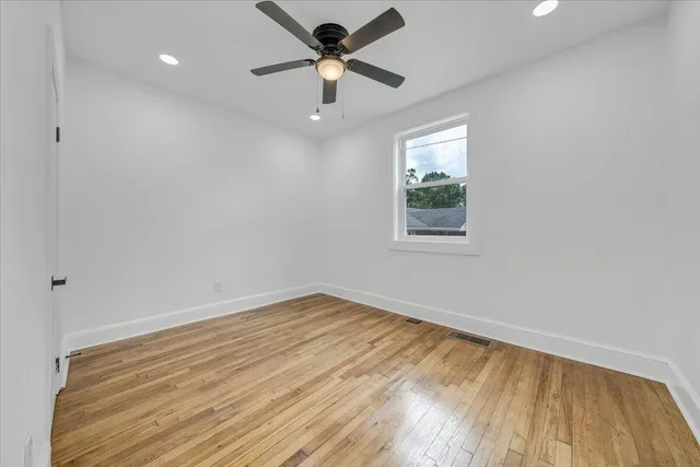 a view of empty room with wooden floor and fan