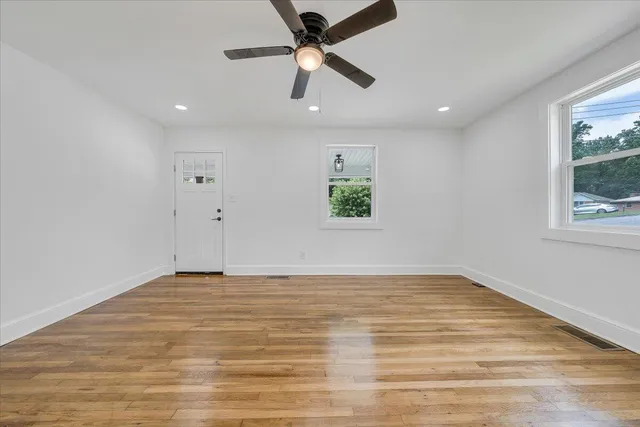 a view of an empty room with window and wooden floor
