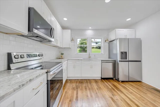 a kitchen with a refrigerator a sink and wooden floor