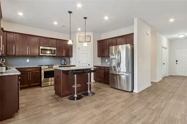 a kitchen with stainless steel appliances granite countertop a stove a sink dishwasher and a microwave oven with wooden cabinets