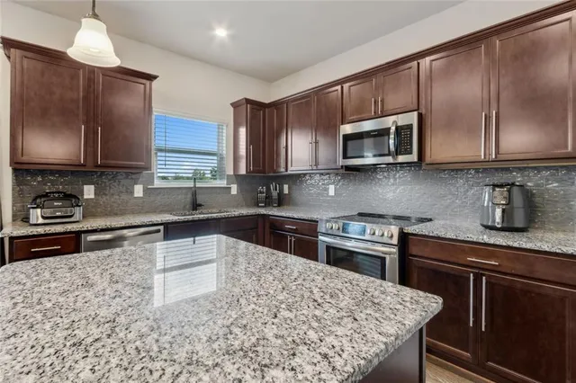 a kitchen with stainless steel appliances granite countertop a sink stove and microwave