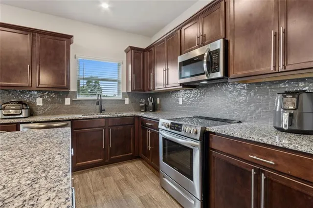 a kitchen with granite countertop cabinets sink and stainless steel appliances