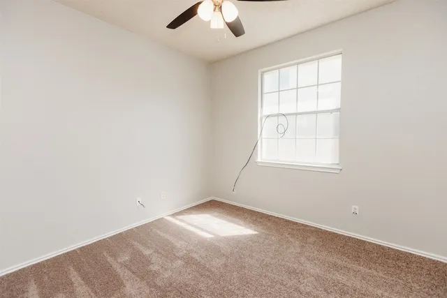 an empty room with a window and a ceiling fan