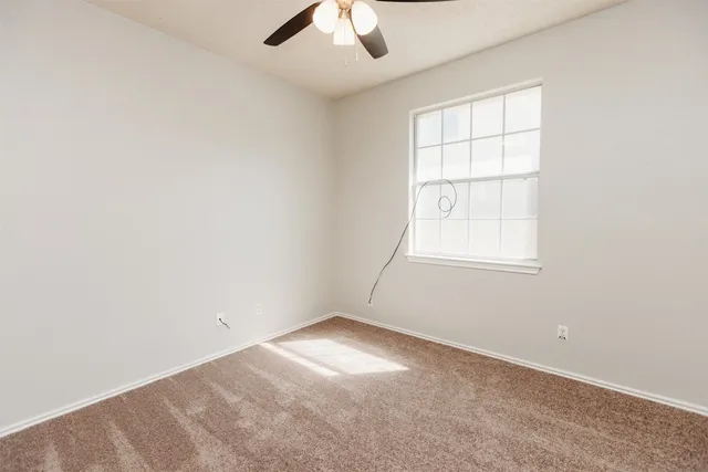 an empty room with a window and a ceiling fan
