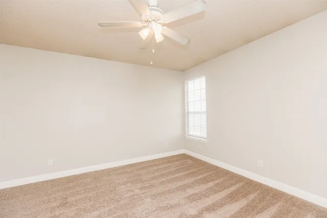 an empty room with a window and a ceiling fan