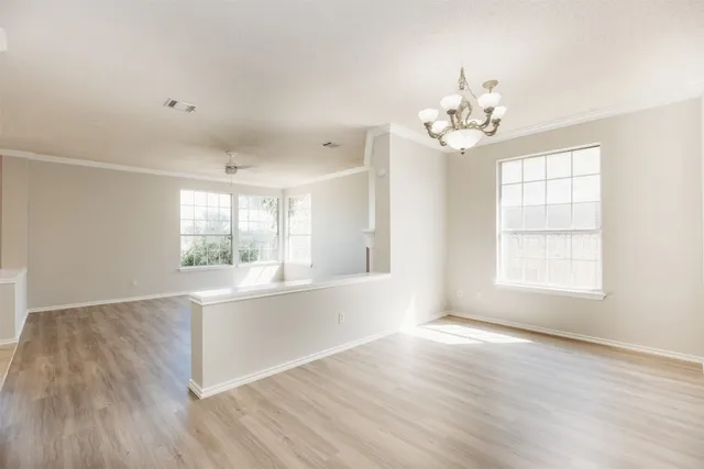 a view of an empty room with a window and wooden floor